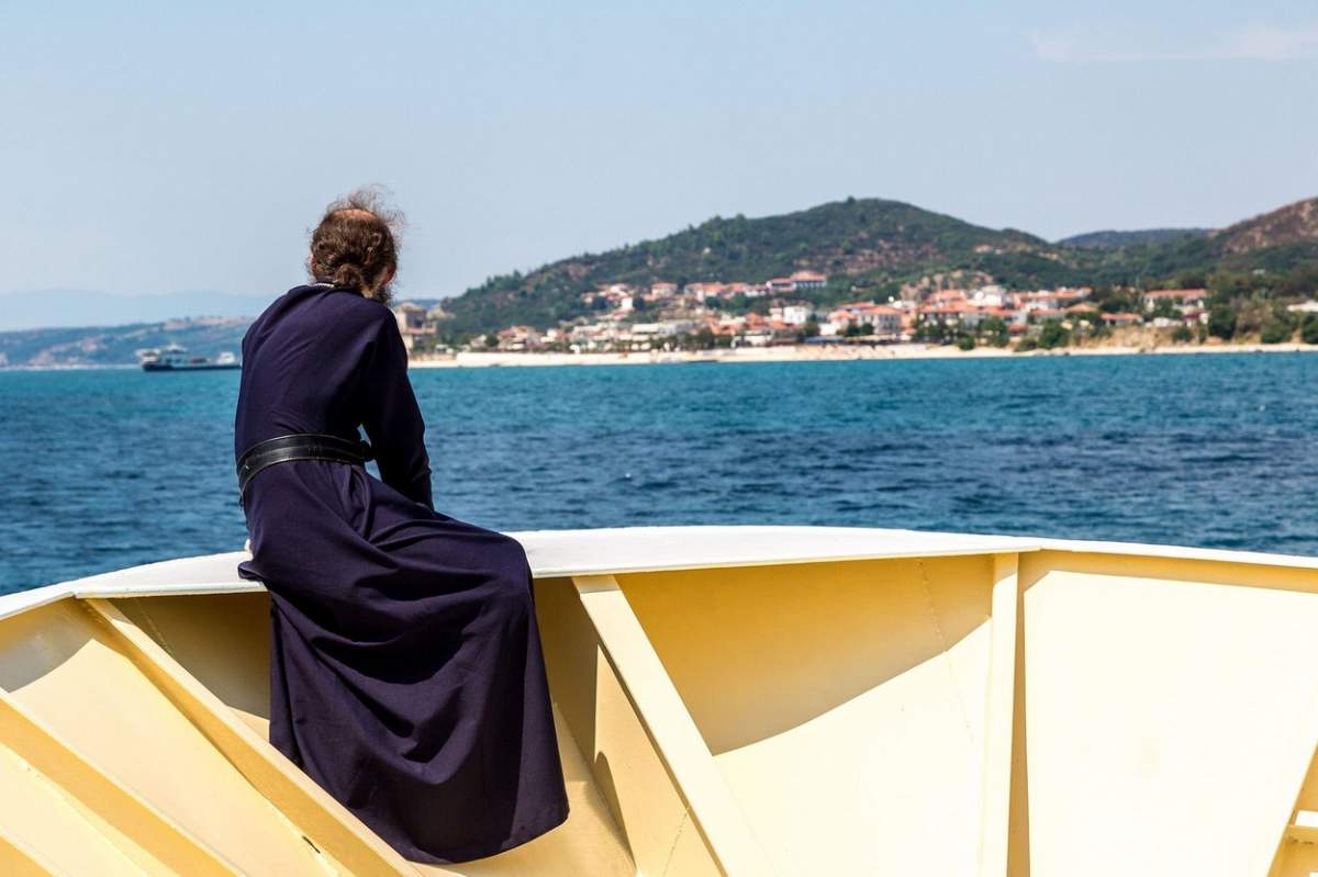 Bătrân călugăr se uită la munții Athos pe o navă într-o zi de vară