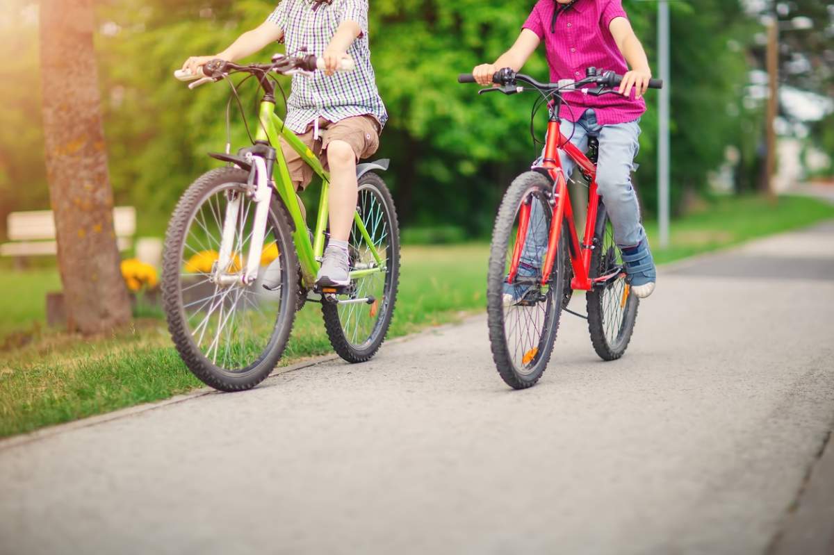 Doi băieți mergând pe bicicletele lor de-a lungul unui drum asfaltat