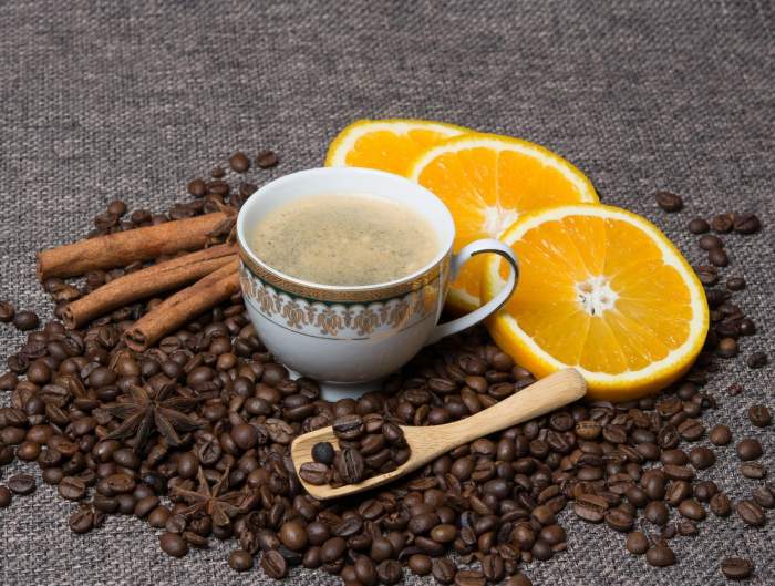 O ceașcă albă de cafea, portocale și boabe de cafea