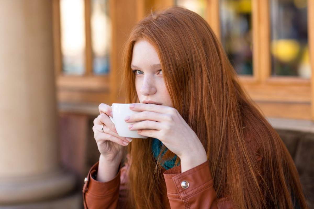 O fată bea dintr-o ceașcă albă de ceai