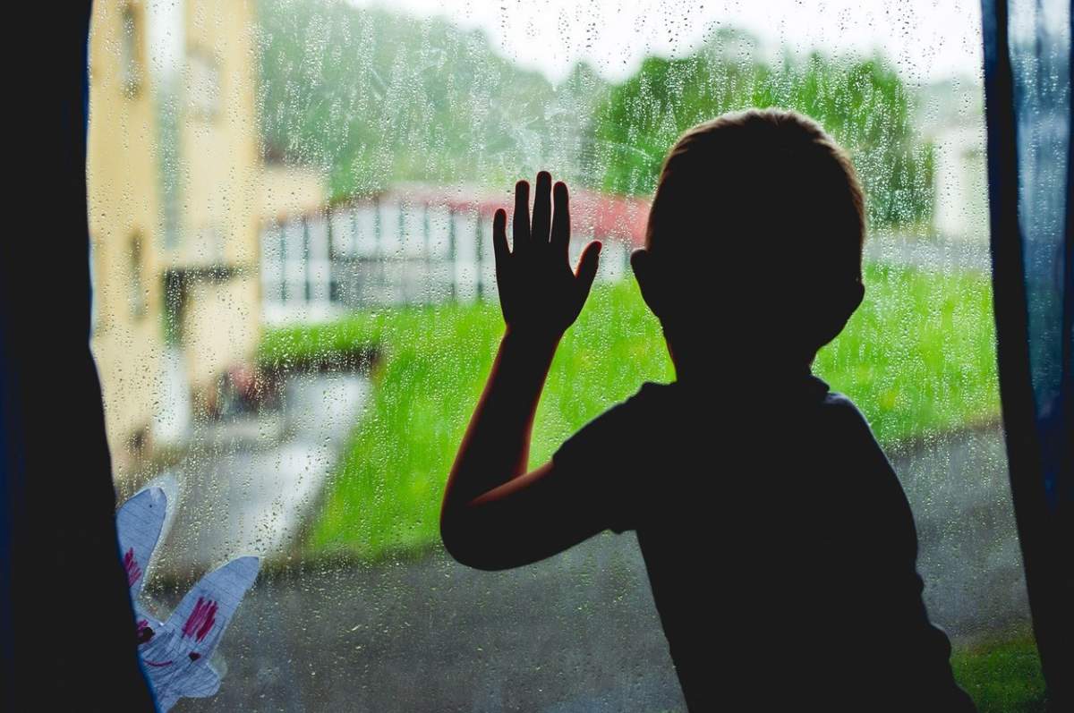 Un copil se uită pe geam