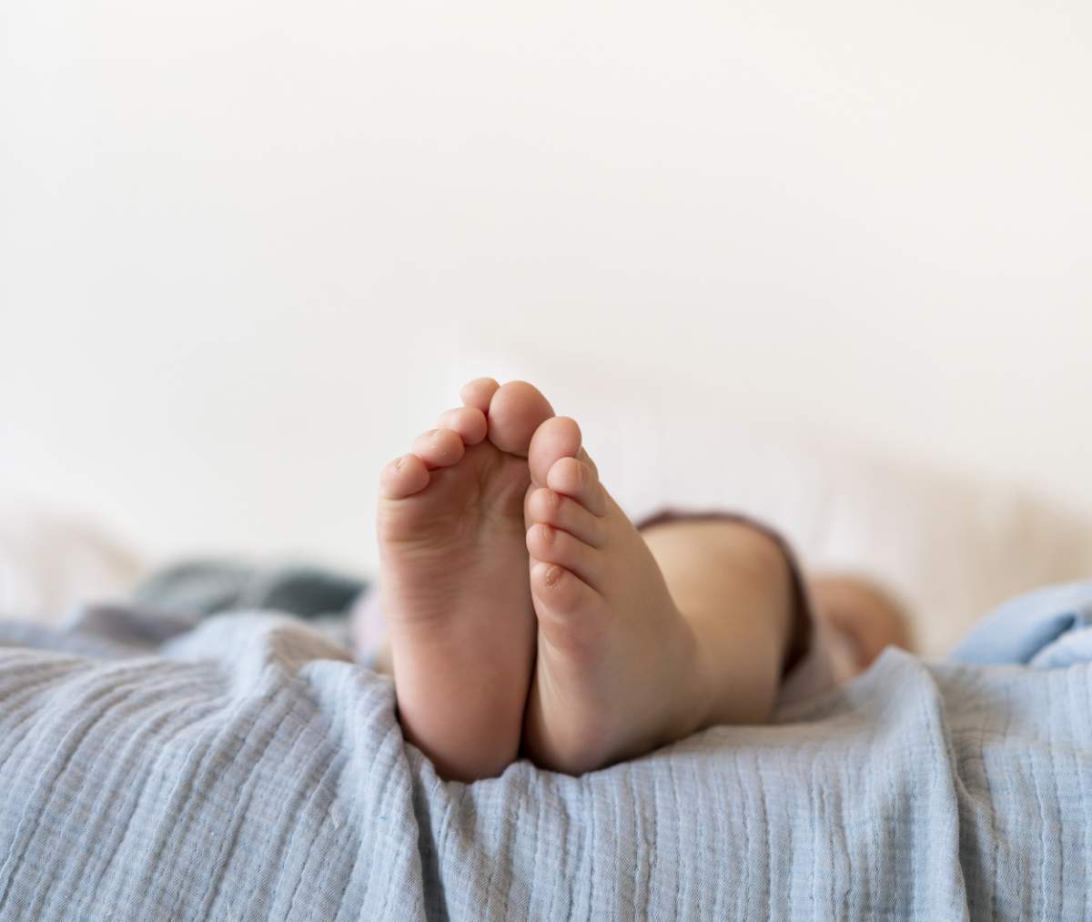 picioarele bebelușului stând în pat