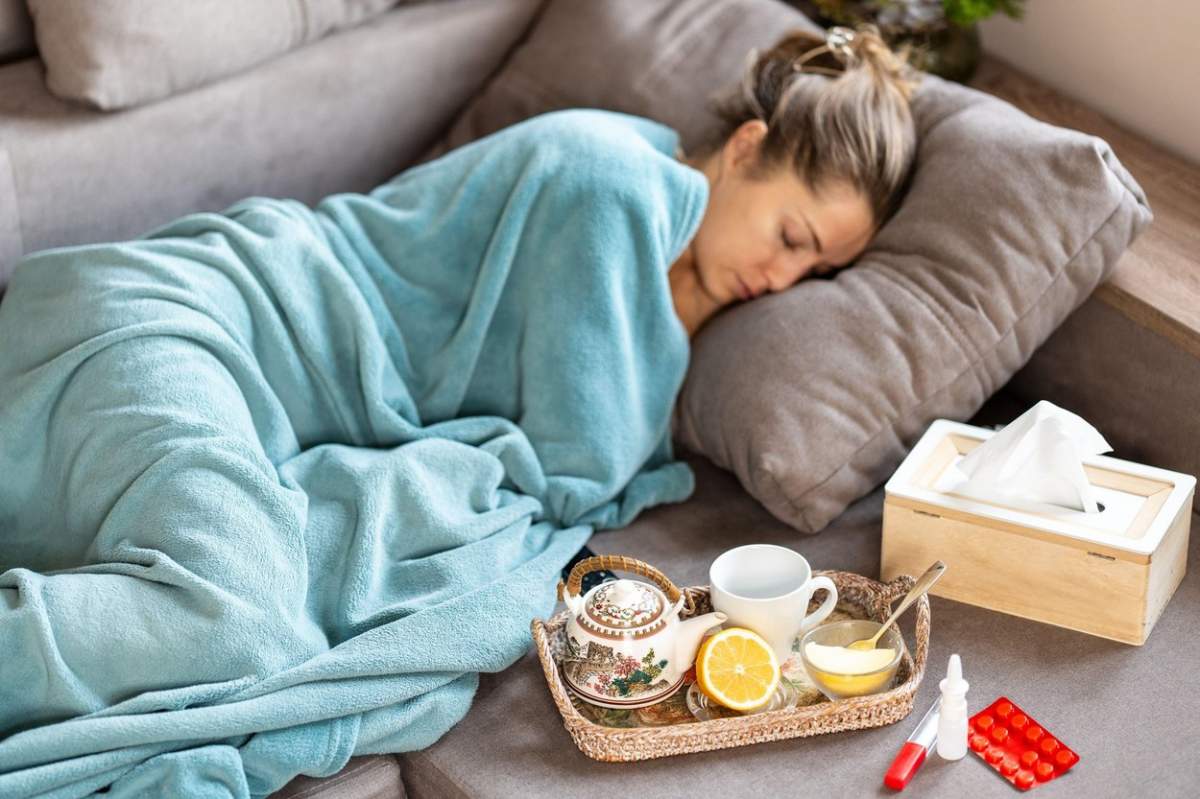 Gripa epidemică. O femeie bolnavă doarme sub o pătură pe canapea.