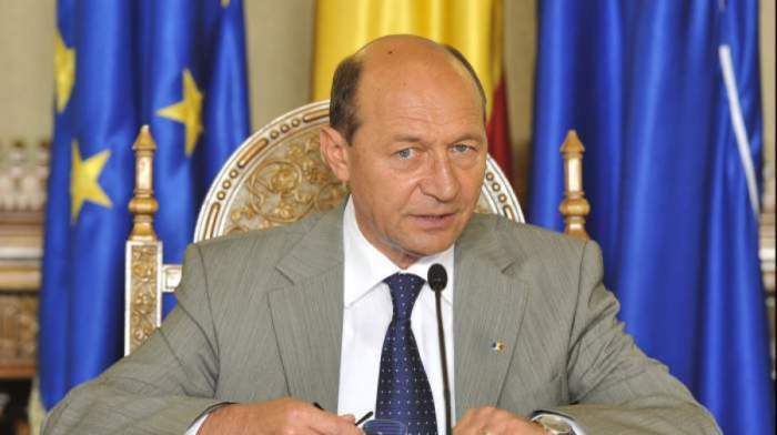 Traian Băsescu cu steagul României în spate, pe un scaun