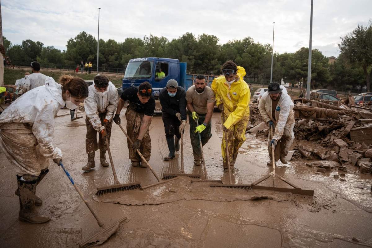 Mai multe persoane îndepărtează noroiul cu perii în Alfafar, pe 9 noiembrie 2024, în Alfafar, Valencia, Comunitatea Valenciană (Spania).