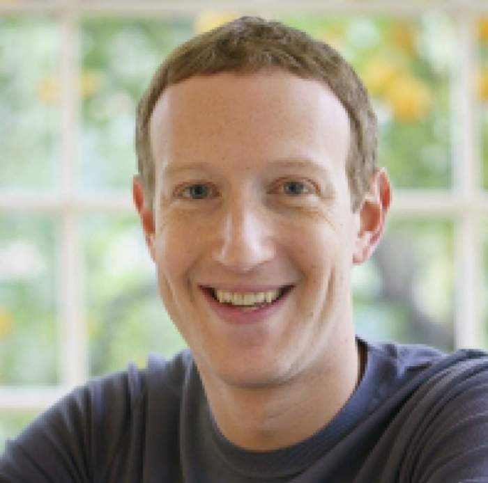 Mark Zuckerberg râde, îmbrăcat în tricou