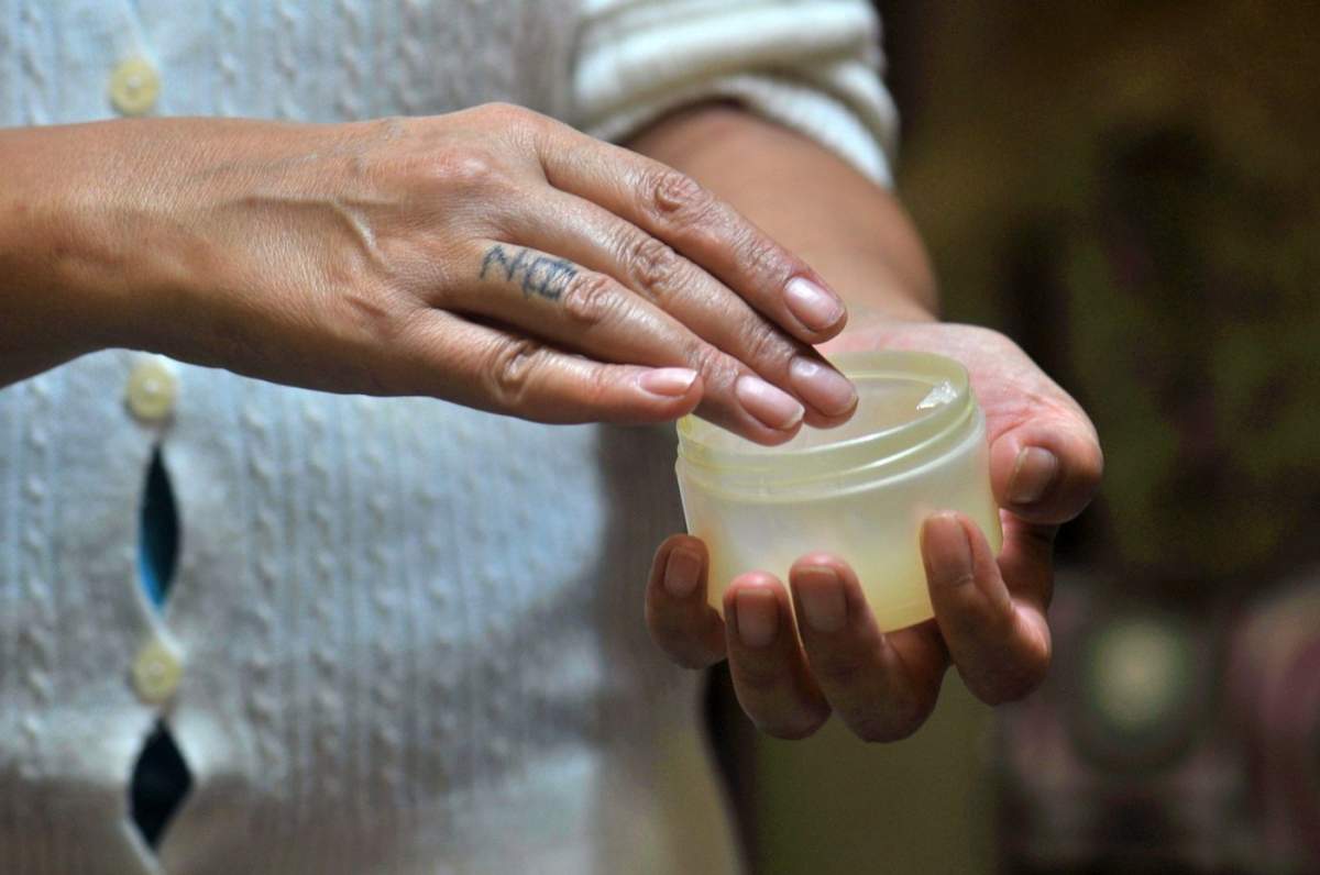 Mâinile unei femei aplicând crema de mâini hidratantă