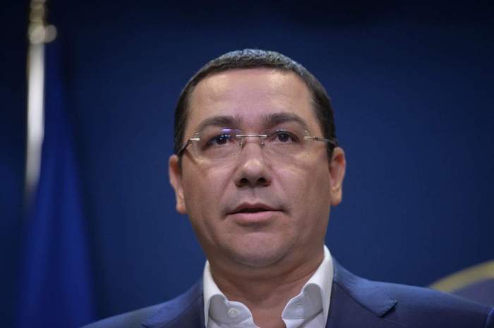 Victor Ponta se uită în sus cu un fundal albastru în spate