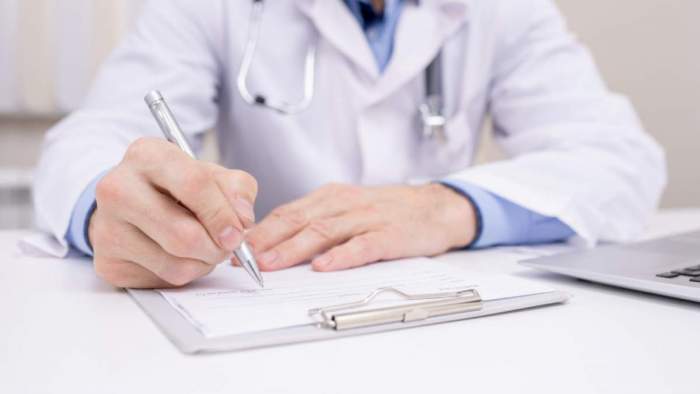 Un medic scrie pe un document