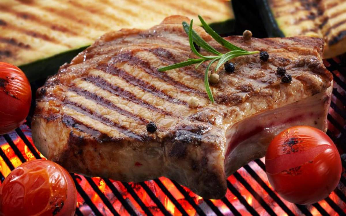 Imagine cu o bucata de carne de porc la grătar si niște roșii