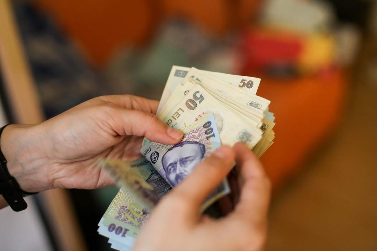 Un om ține în mână mai mulți bani românești