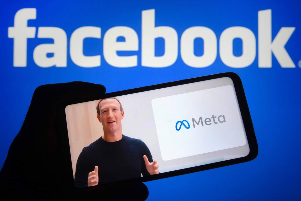Mark Zuckerberg pe un telefon și pe spate un fundal cu Facebook