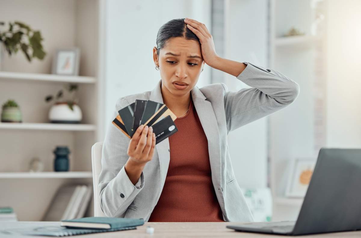 Stres financiar, femeie îngrijorată și frustrată care ține în mână carduri bancare la birou