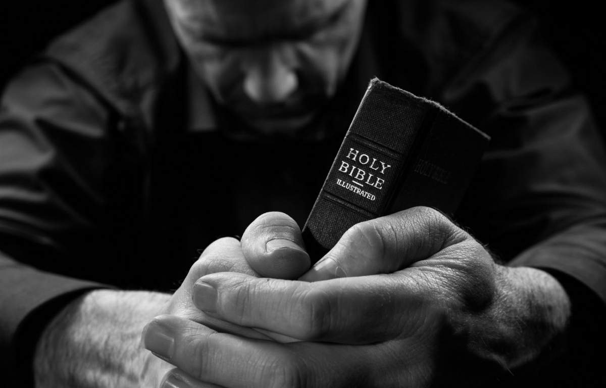 un bărbat care se roagă și o Biblie