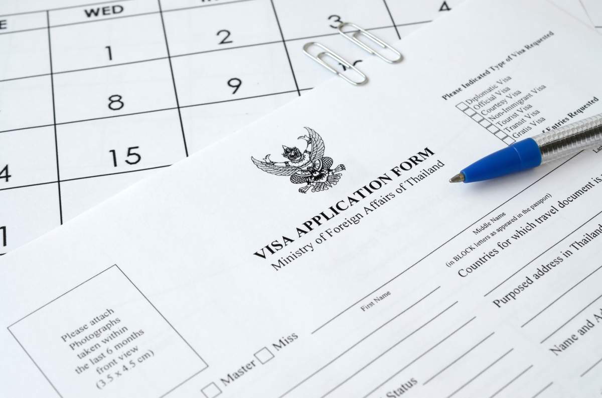 Formularul de cerere de viză pentru Thailanda și pix albastru pe pagina de calendar pe hârtie
