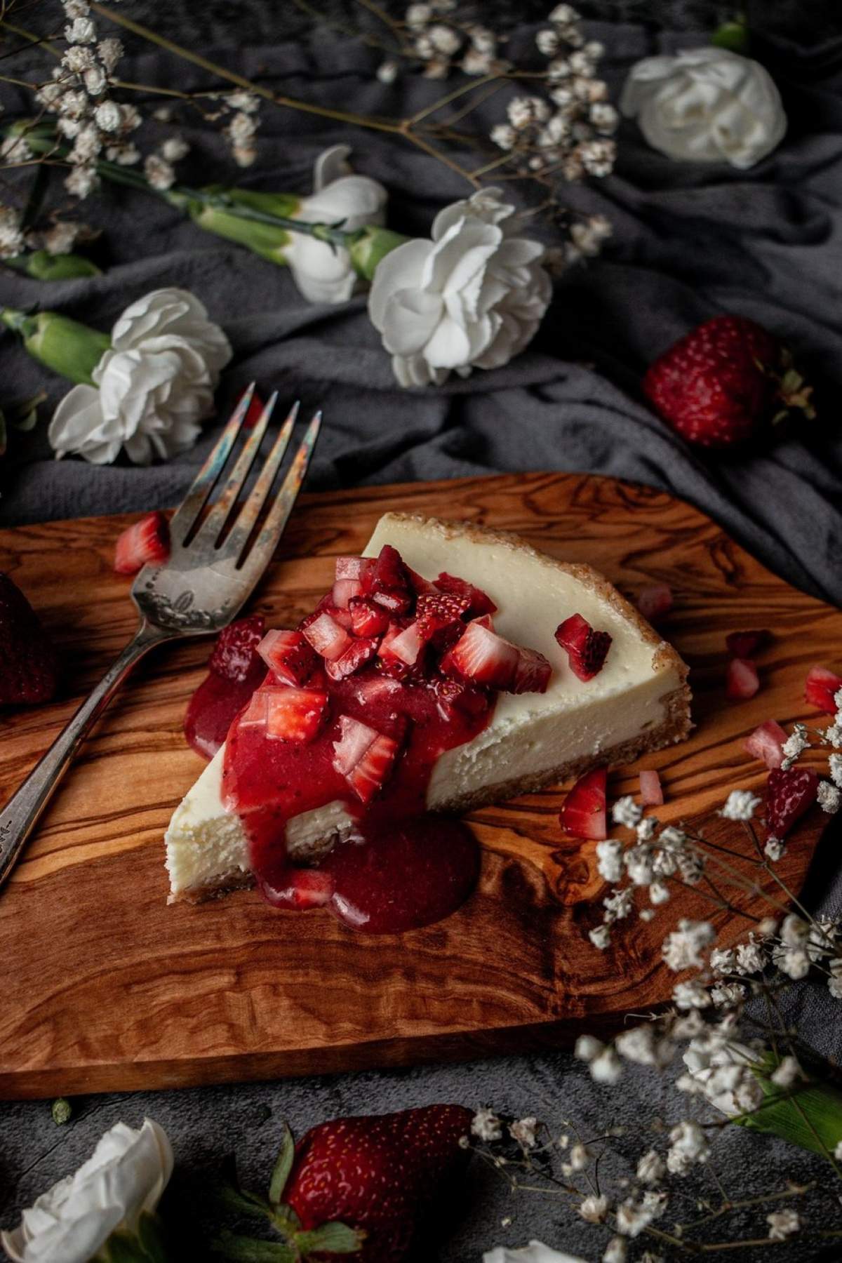 Sos de căpșuni care se scurge de pe marginea unei felii de cheesecake simplu