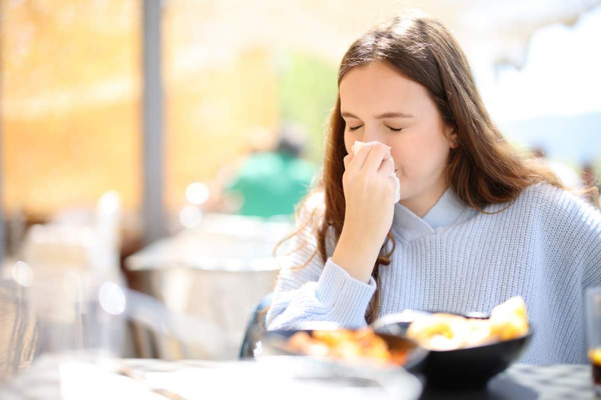 Clientul unui restaurant bolnav suflă pe șervețele pe o terasă