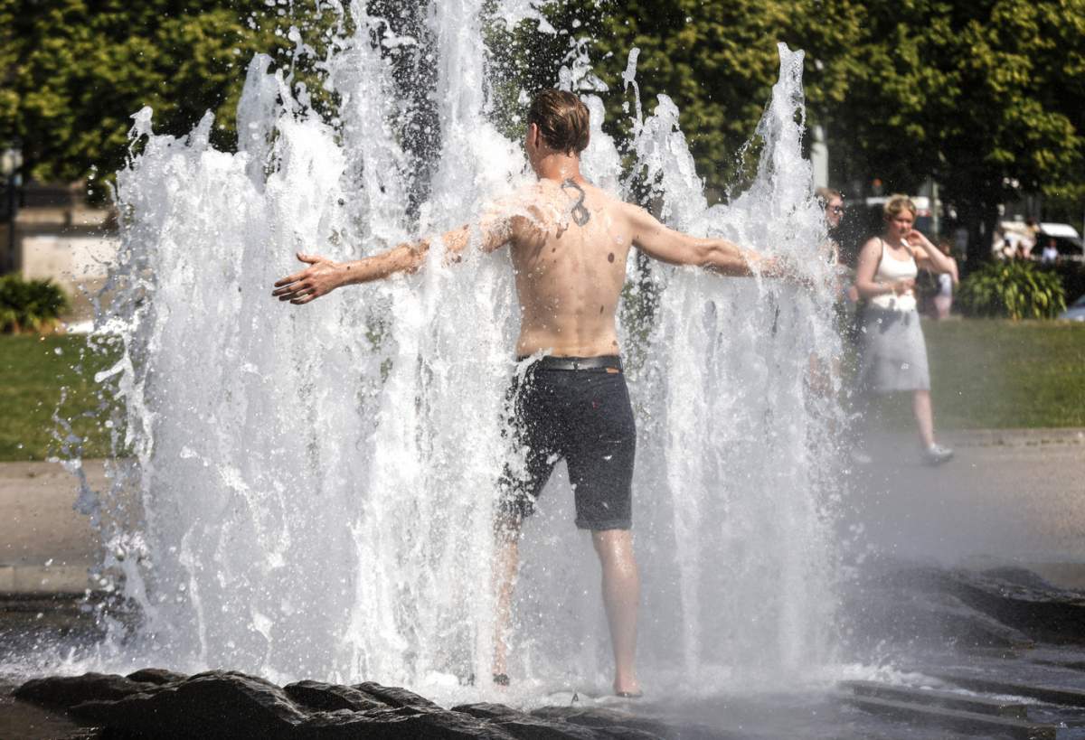 Un bărbat se răcorește la o fântână din Lustgarten din Berlin