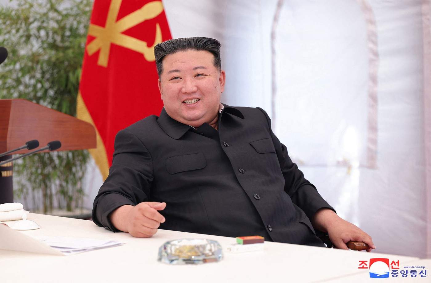 Kim Jong Un la un pupitru, îmbrăcat în costum negru