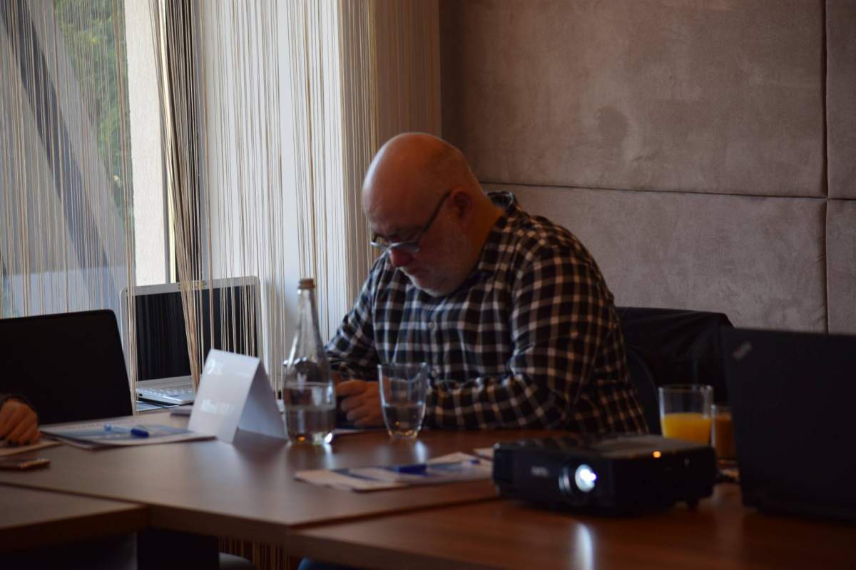 Alfred Bulai la o masă, se uită în jos Alfred Bulai la o masă