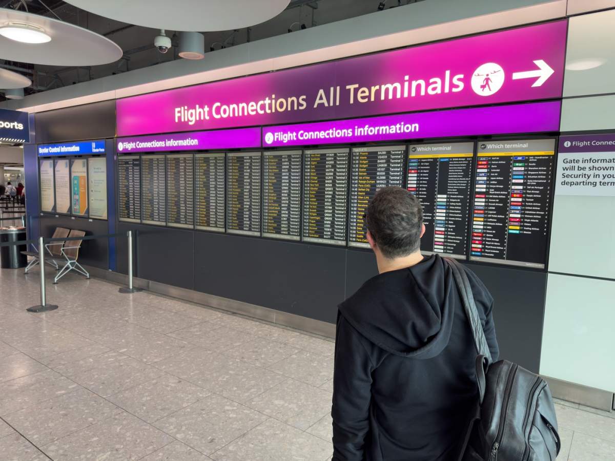 Un călător se uită la ecranul cu informații despre conexiunile de zbor de la Aeroportul Heathrow, Londra, Anglia.