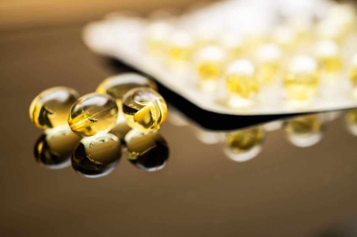 Capsule transparente galbene de vitamina D și ulei de pește omega-3, expuse într-un blister vizibil, subliniind suplimentele alimentare pentru sănătate și bunăstare