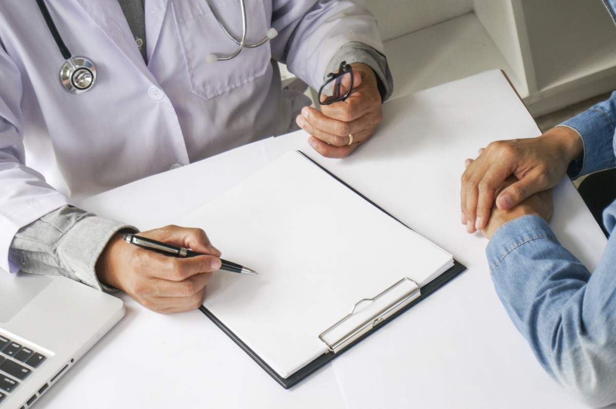 Medic ținând în mână un pachet cu diferite blistere de comprimate pentru pacient. Prescrie medicamente. Concept de vindecare a bolii. Ambalaj de comprimate și pastile pe masă.