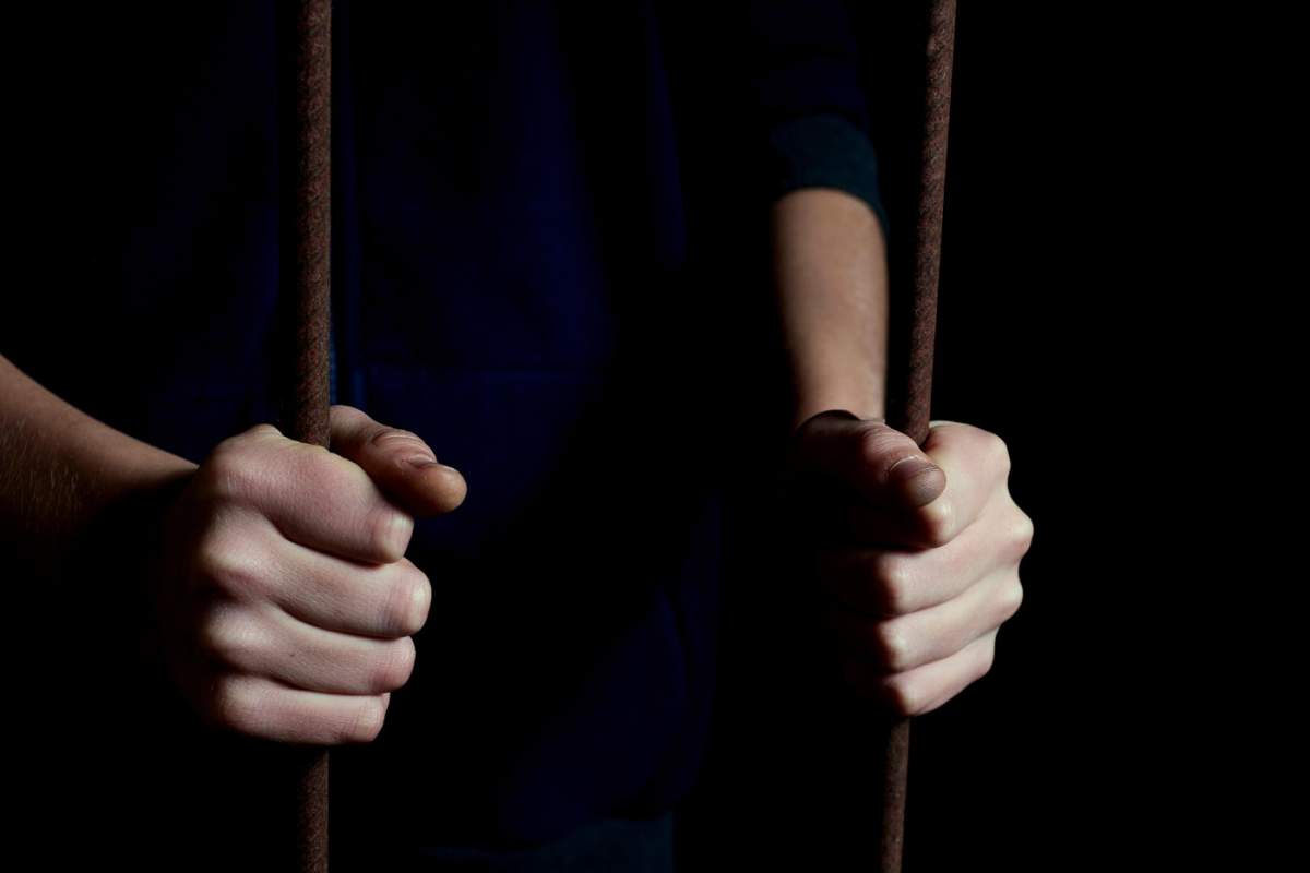 Mâini de copil ținând bare într-un loc întunecat de ascunzătoare. Imagine conceptuală a unui copil răpit