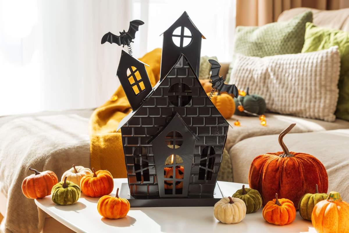 Decor de Halloween cu dovleci și casă bântuită pe măsuța de cafea lângă canapeaua confortabilă