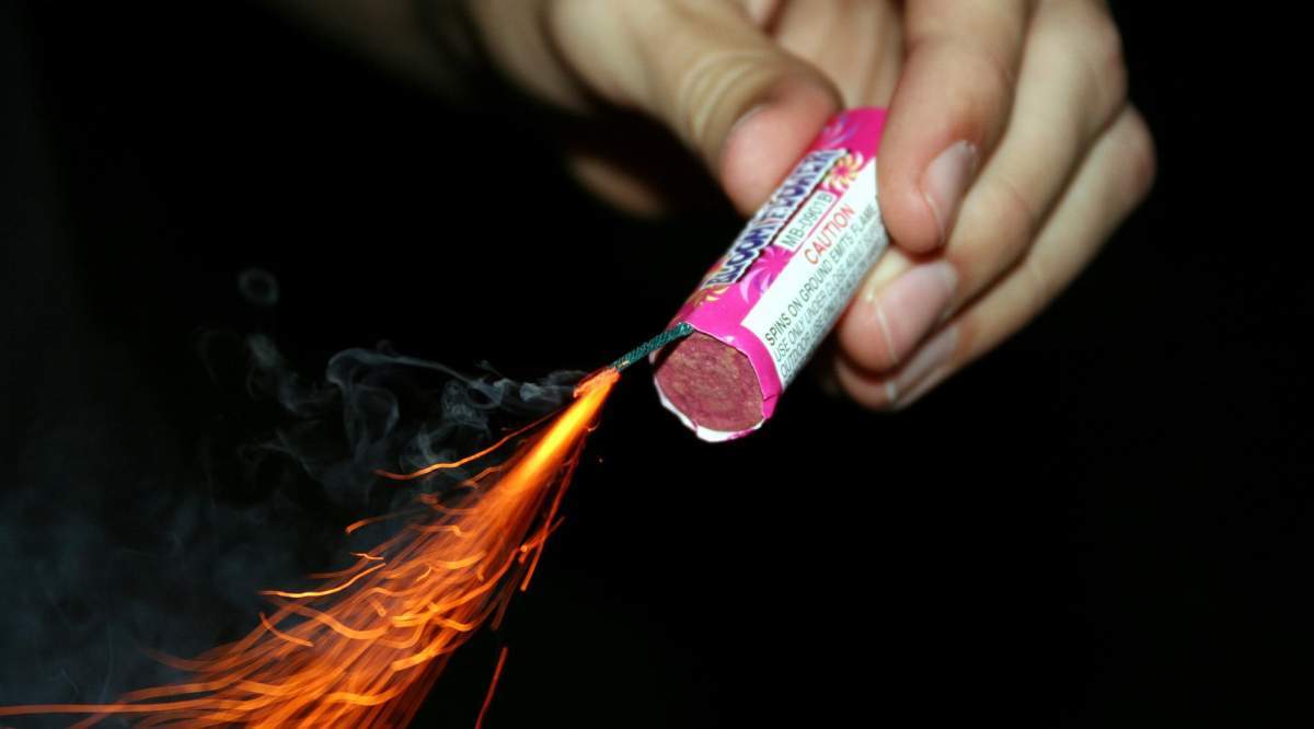 Un copil ține în mână o petardă