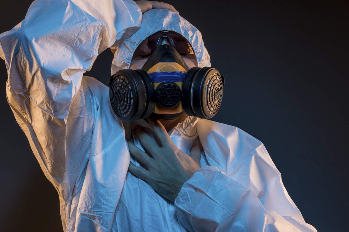 Conceptul de infecție virală. Bărbat în costum de protecție și mască antigaz cu ochelari. Ebola, gaze toxice, război biologic, infecții și boli