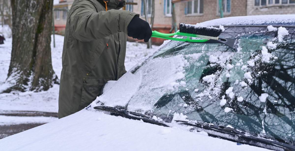 un bărbat care curăță mașina de zăpadă, o perie cu resturi de gheață
