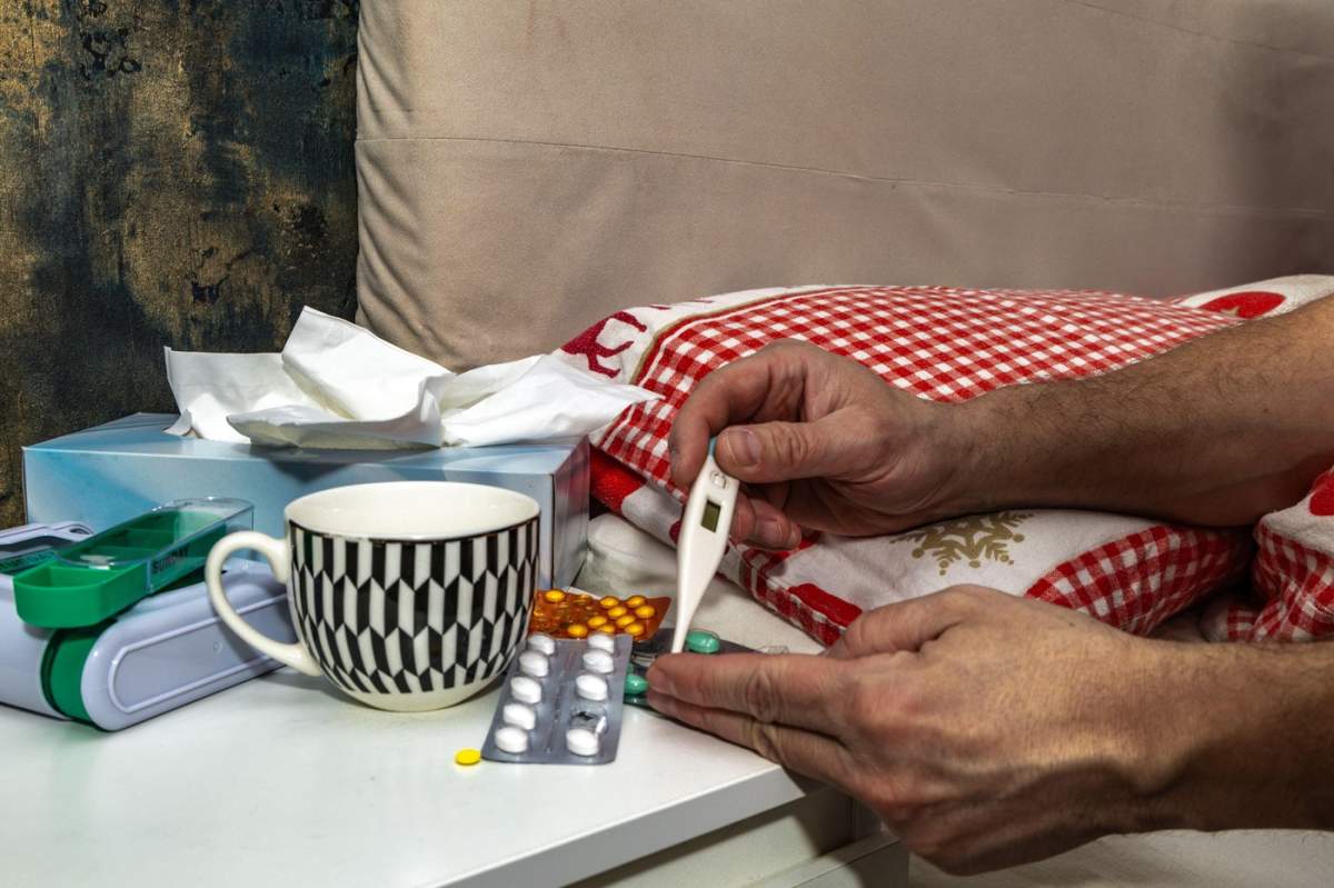 Un bărbat zace bolnav în pat, înconjurat de un grup de oameni, luând medicamente de la un bărbat răcit, analgezice, medicamente prescrise, antigripale, antirăceli, de pe dulap.