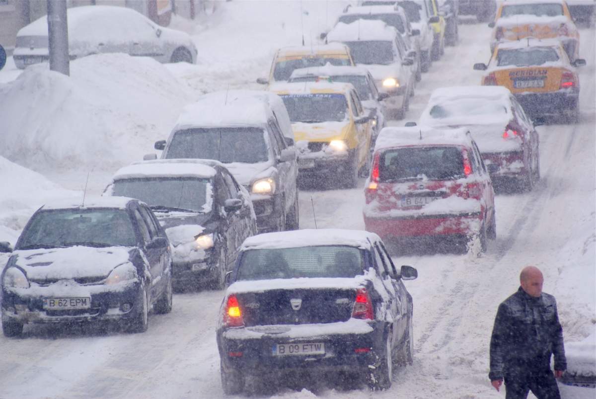 Mașinile și pietonii se luptă pe drumuri în condiții de viscol.