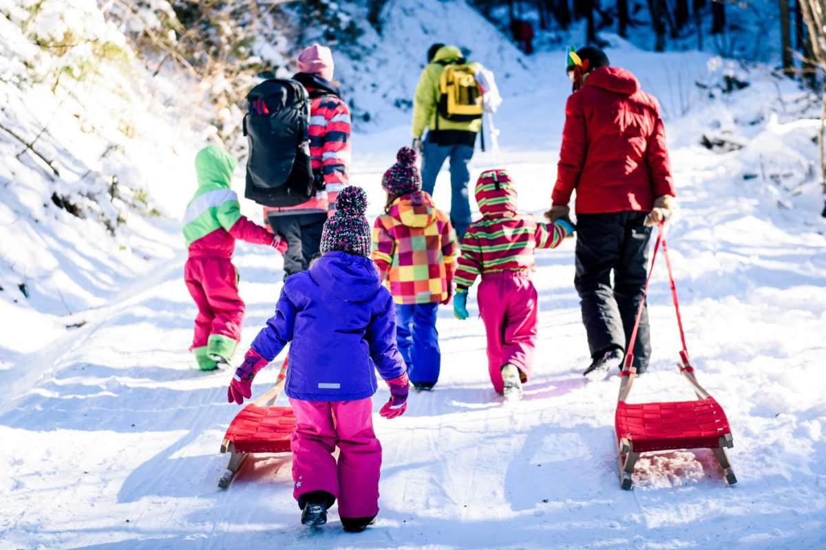 copii care se dau cu sania insotiti de parinti