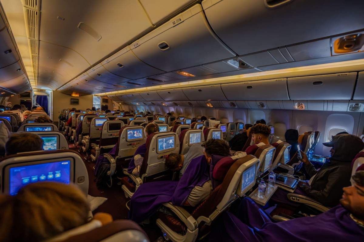 În interiorul unui avion Thai Airways, o atmosferă calmă și relaxată, cu fiecare loc ocupat, favorizând o atmosferă liniștitoare și somnoroasă