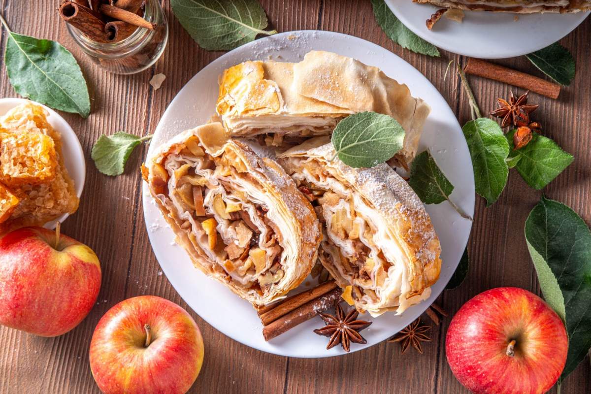 Strudel de mere de toamnă parfumat de casă cu mere caramelizate, stafide, nuci, miere, condimente de scorțișoară, pe farfurie pe masa de bucătărie copie spațiu