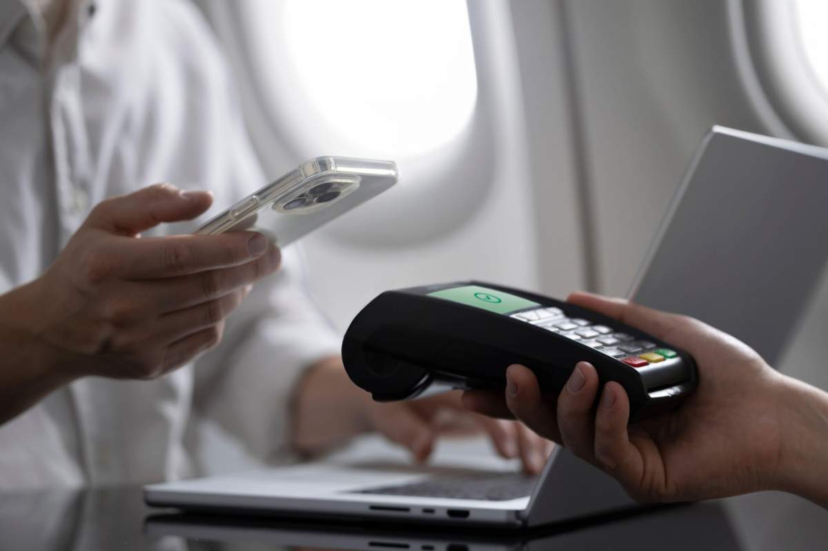 Un bărbat face o achiziție într-un avion folosind plata mobilă convenabilă cu tehnologia tap-to-pay fără contact. Imaginea surprinde ușurința și eficiența