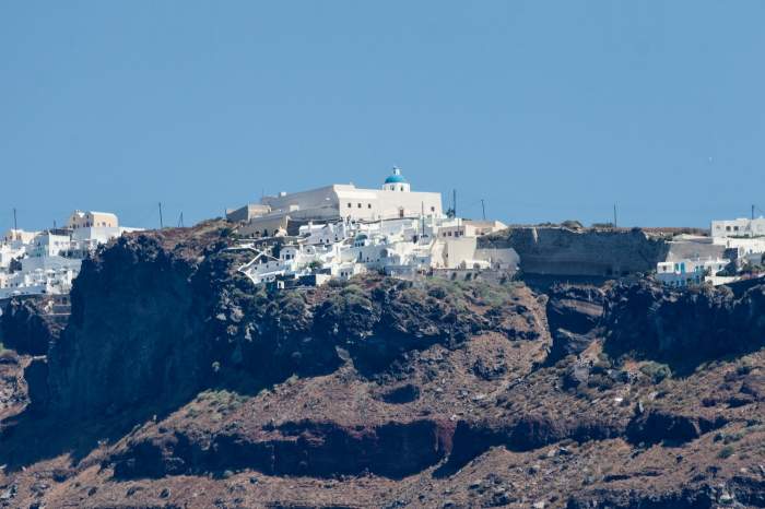 Peisajul uscat al insulei Thira, orașul Fira la orizont peste dealuri. Insula grecească Thira, Santorini, Grecia