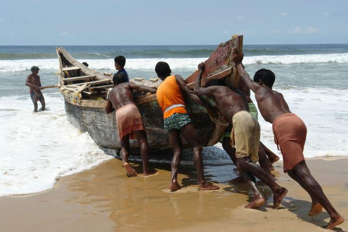 Pescarii indieni împing barca spre mare pentru pescuit 14 octombrie 2006 în Kerala, India.