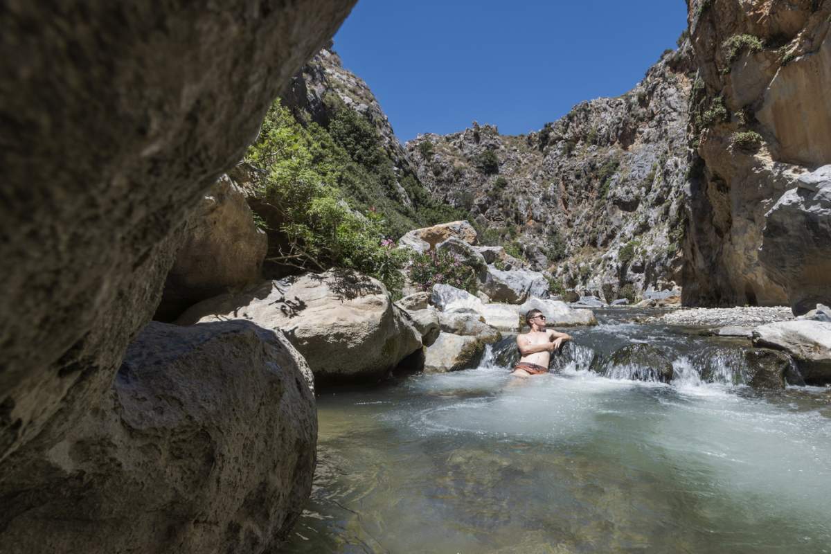 Plaja Preveli, la capătul defileului Kourtaliotiko, Coasta de Sud, Creta, Insulele Grecești, Grecia, Europa. tânăr stând în râu, Europa