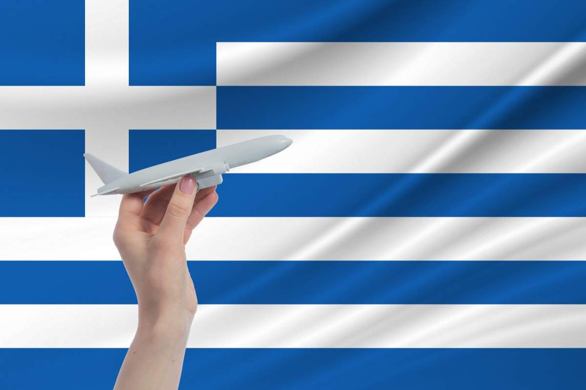 Avion în mână cu steagul național al Greciei. Călătorie în Grecia