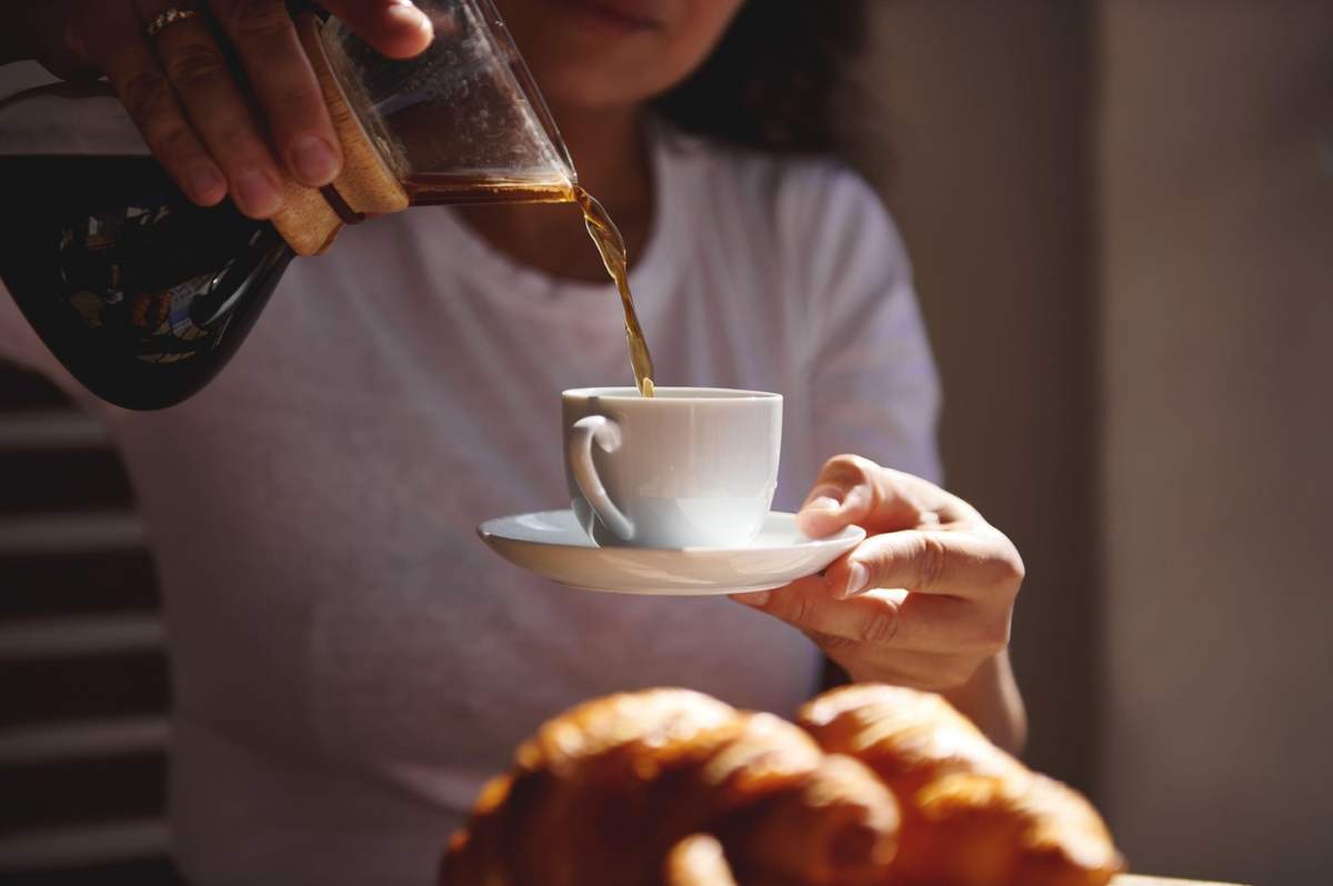 O scenă confortabilă în care o persoană se bucură de cafeaua de dimineață cu croissante