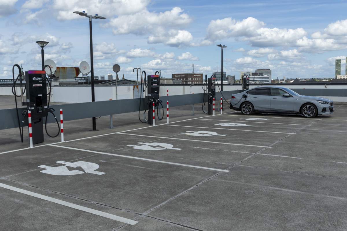Mobilitate, încărcare electrică Hamburg, mașină la o stație de încărcare pe un cer albastru cu nori, stație de încărcare pentru vehicule electrice în parcarea MediaMarkt Tech Village, Hamburg, Germania