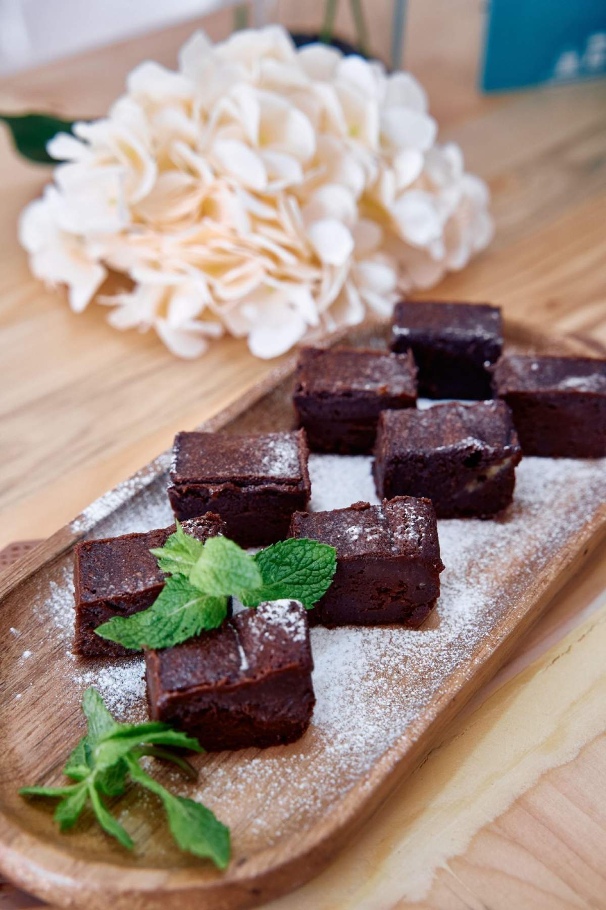 Brownies decadente cu ciocolată, pudrate cu zahăr pudră și ornate cu mentă