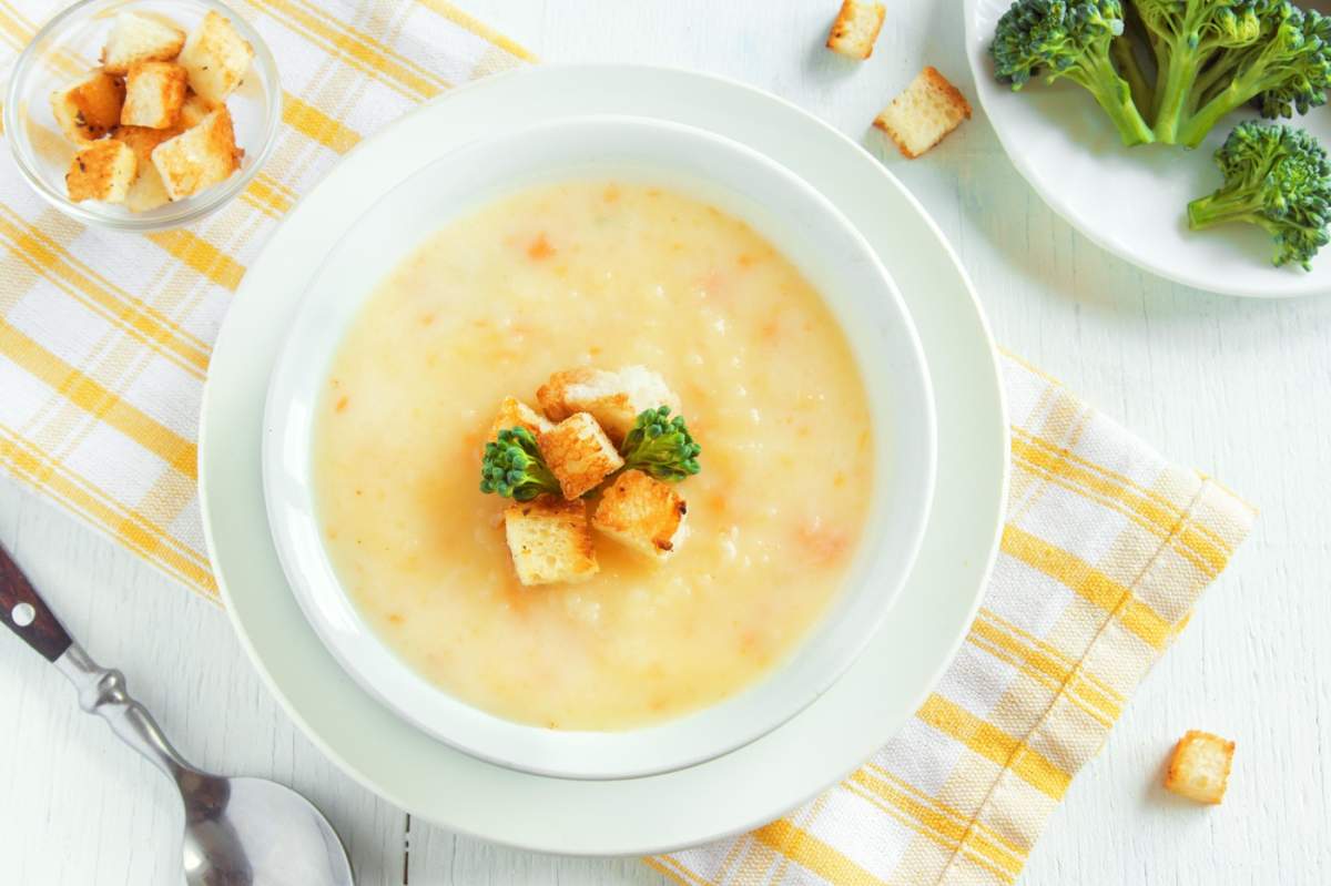 Supă cremă de legume și brânză cheddar cu broccoli și crutoane într-un bol alb, prim-plan - mâncare vegetariană sănătoasă, preparată în casă