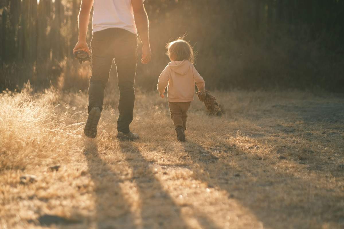 Tată plimbându-se cu fiul mic afară la apus