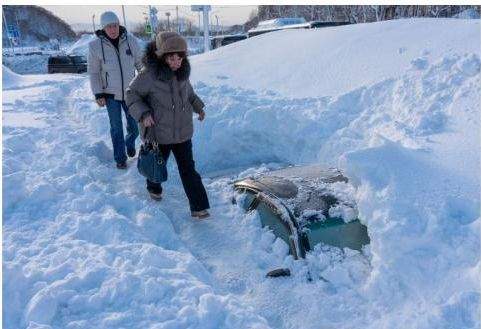 Oamenii merg pe mașinile acoperite cu zăpadă