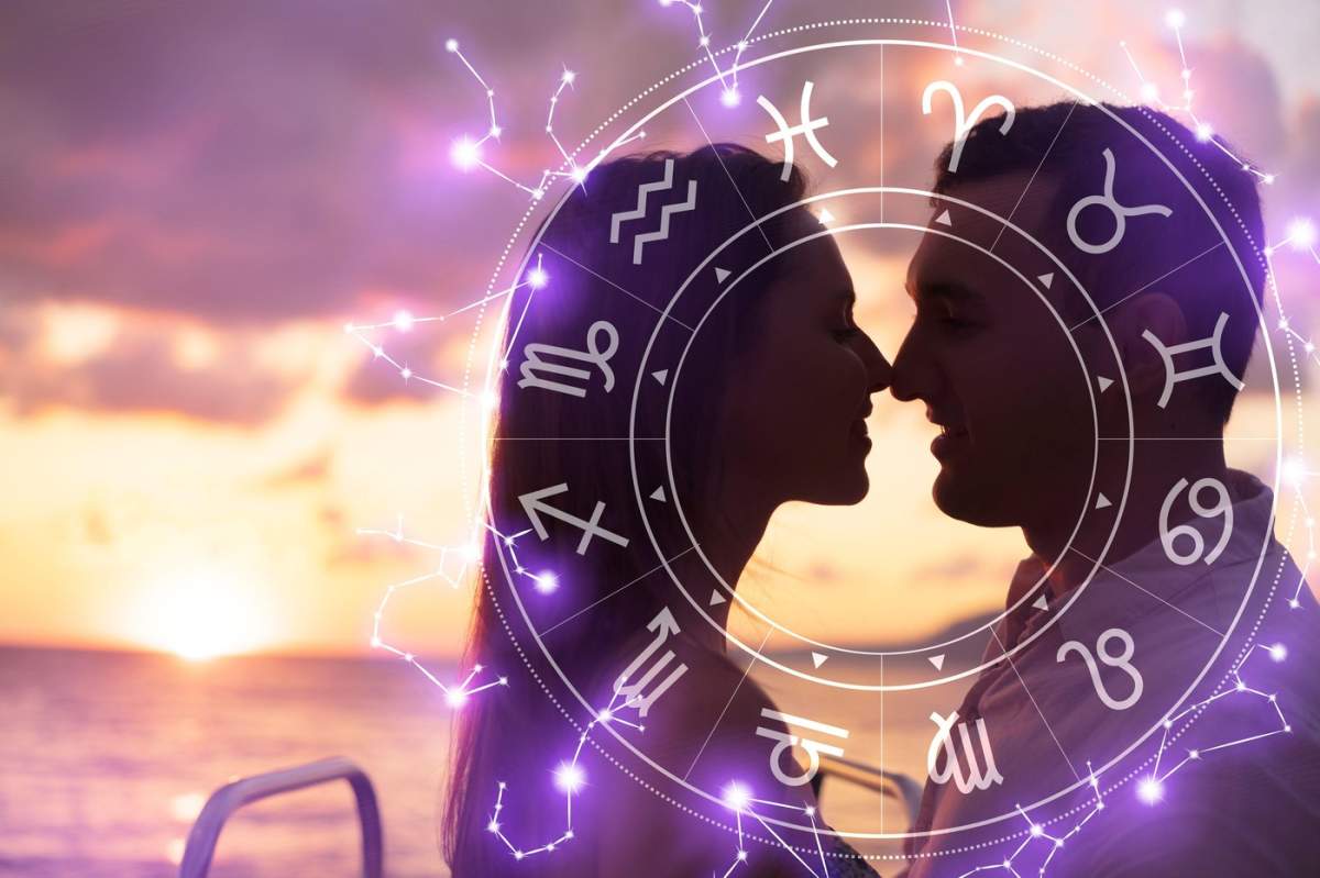Silueta unui cuplu cu semne zodiacale, pe fundalul unui apus de soare la plajă