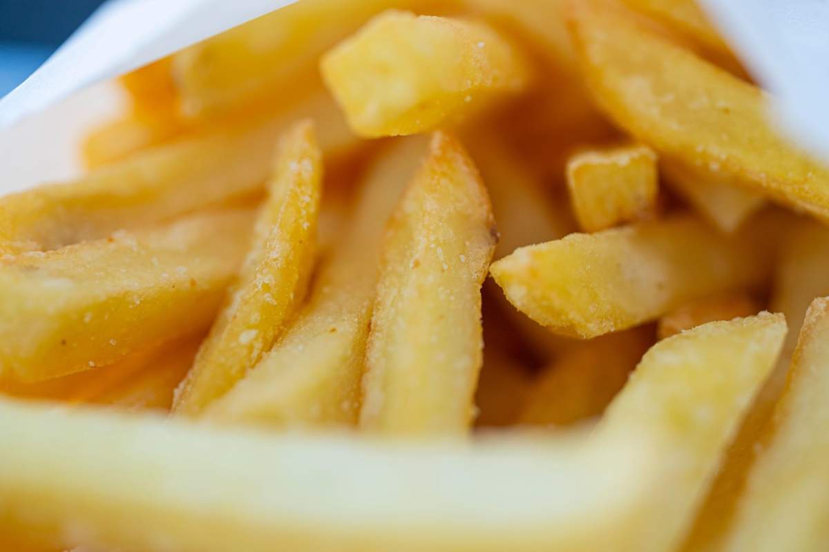 Cartofi prăjiți calzi și sărați, serviți ca garnitură într-un restaurant fast-food cu atmosferă relaxată.